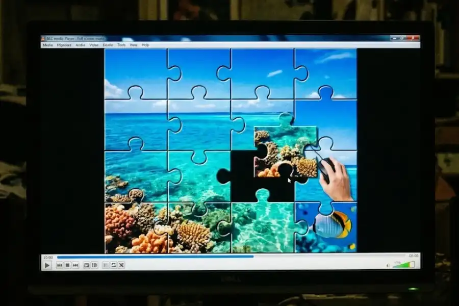 Hand clicking mouse while playing a VLC puzzle game with tropical ocean video tiles on screen.