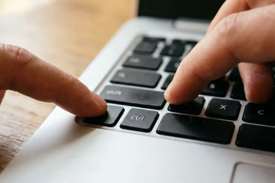 Close-up of fingertips pressing keyboard shortcut keys on a Chromebook keyboard