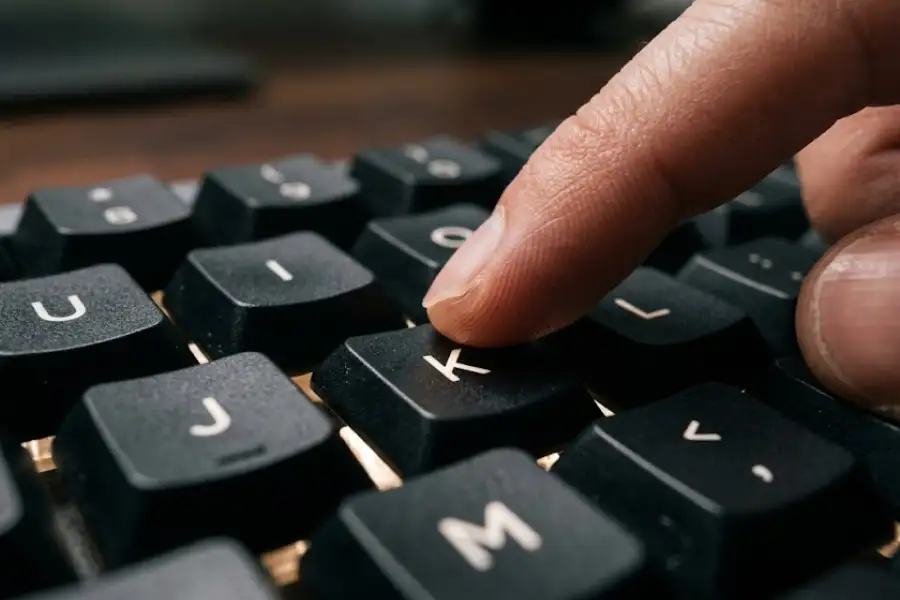 YouTube Keyboard Shortcuts: 40+ Hidden Keys That Save Hours 2 Close-up of a finger pressing the K key on a backlit keyboard with J and L keys visible nearby