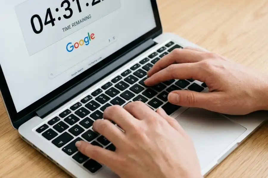 Interactive Google Searches: 30+ Games, Hidden Tools, and Easter Eggs Worth Trying 2 Close-up of hands typing on a laptop with a Google search results page showing a countdown timer tool at the top of the screen