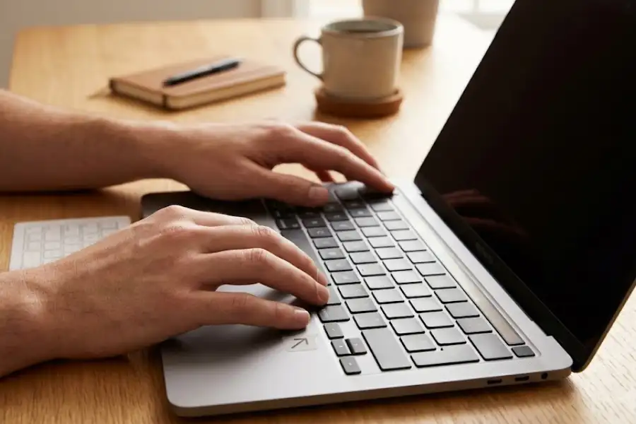 Person pressing SMC reset key combination on a MacBook Pro keyboard on a wooden desk