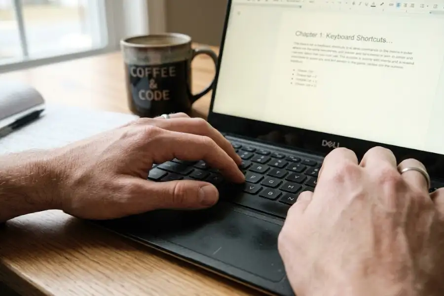 Close-up of hands typing a keyboard shortcut on a laptop keyboard