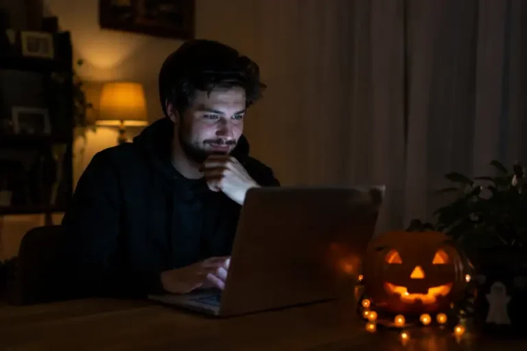Person playing the Google Doodle ghost game on a laptop at night with Halloween decorations nearby