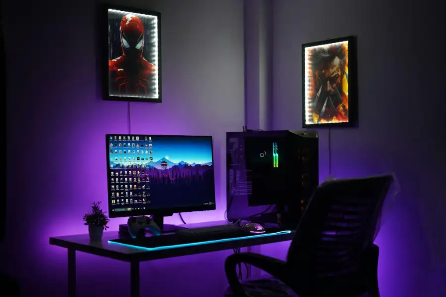 Modern gaming PC setup with a monitor, RGB lighting, gaming chair, and wall art.