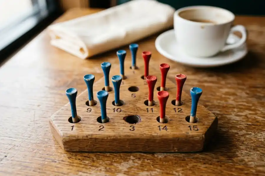 Wooden triangle peg game board with golf tees on a diner table
